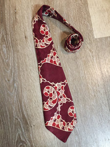 Kingspier Vintage - Van Heussen de Luxe in burgundy, red, cream and brown design on a subtle checkerboard background. Fibres unknown.

Length: 53” 
Width: 4”

This tie is in excellent condition.