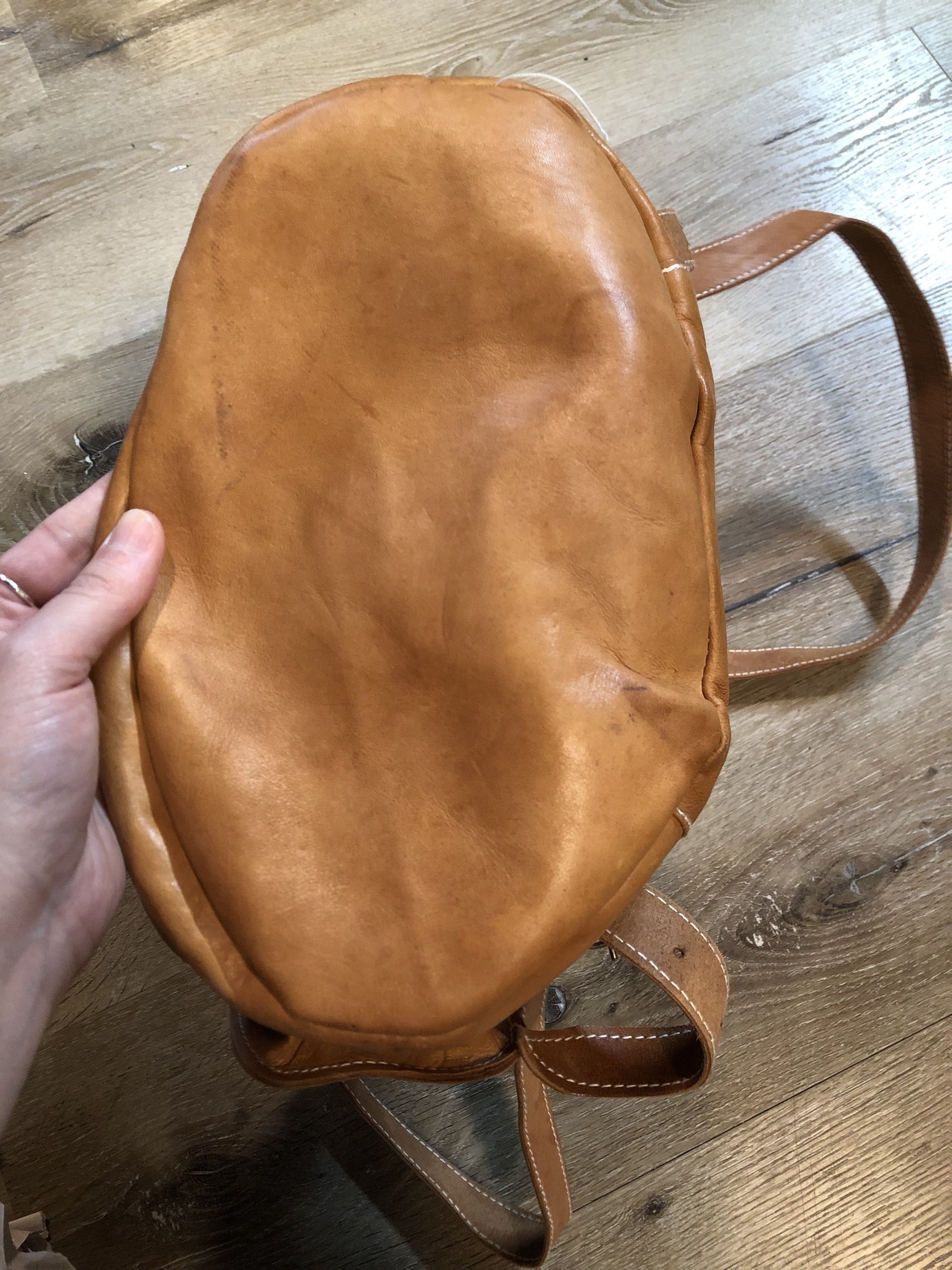 Vintage full grain leather backpack in light brown with top carry handle, flap closure, interior drawstring, three exterior compartments and adjustable shoulder straps Kingspier Vintage