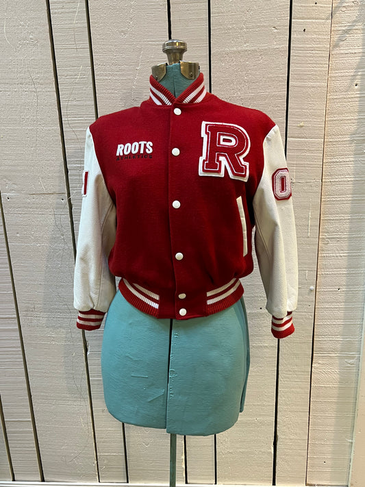 Roots Athletics circa 2000 red and white varsity jacket with wool blend body, leather sleeves, snap closures, two front slash pockets, “R” patch on the chest, Canada flag patch on the arm, “00” patch on the arm and “Canada” written across the back.

Made in Canada
Size Youth Medium