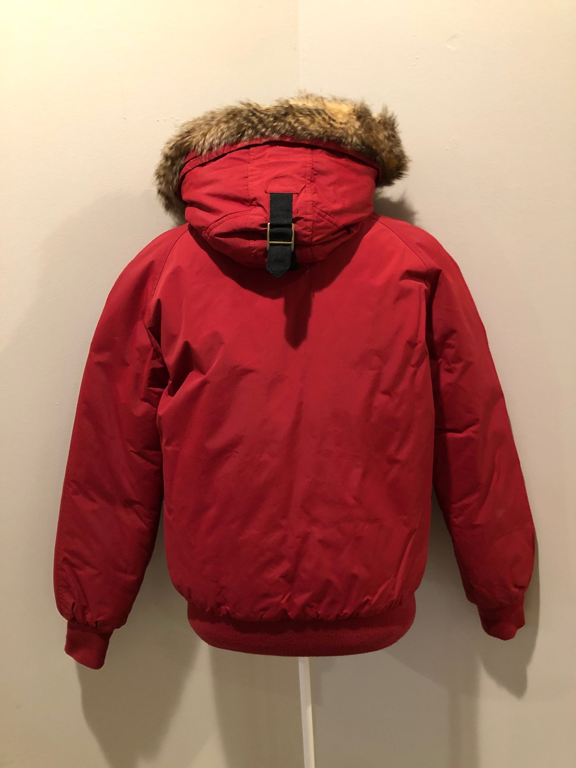 Kingspier Vintage - Roots down-filled bomber jacket in red with faux fur trimmed hood, zipper closure, flap pockets and slash pockets, “Stay Warm Eh” written on the inside pocket. Size medium.