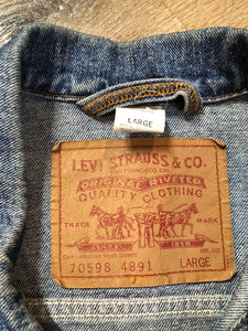 Vintage 1980’s Levi’s medium wash denim trucker jacket with button closures, two flap pockets on the chest, two side pockets and two inside pockets.  Red Tab, 100% cotton, size large -Kingspier Vintage