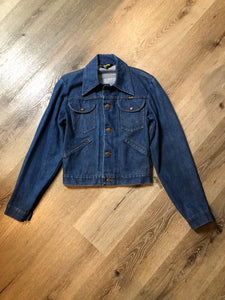 Vintage Wrangler medium wash denim jacket with button closures, two flap pockets on the chest and two hand warmer pockets in the front.  100% cotton, made in Canada, size 32 - Kingspier Vintage