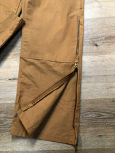 Load image into Gallery viewer, Kingspier Vintage - Berns sleeveless duck canvas overalls in tan brown. Overalls feature adjustable shoulder straps with buckle fastening, hammer loop, patch pocket on the chest, side utility pockets, pockets in the front and back, overalls button at the waist and have reinforced knees. Size 32X32.
