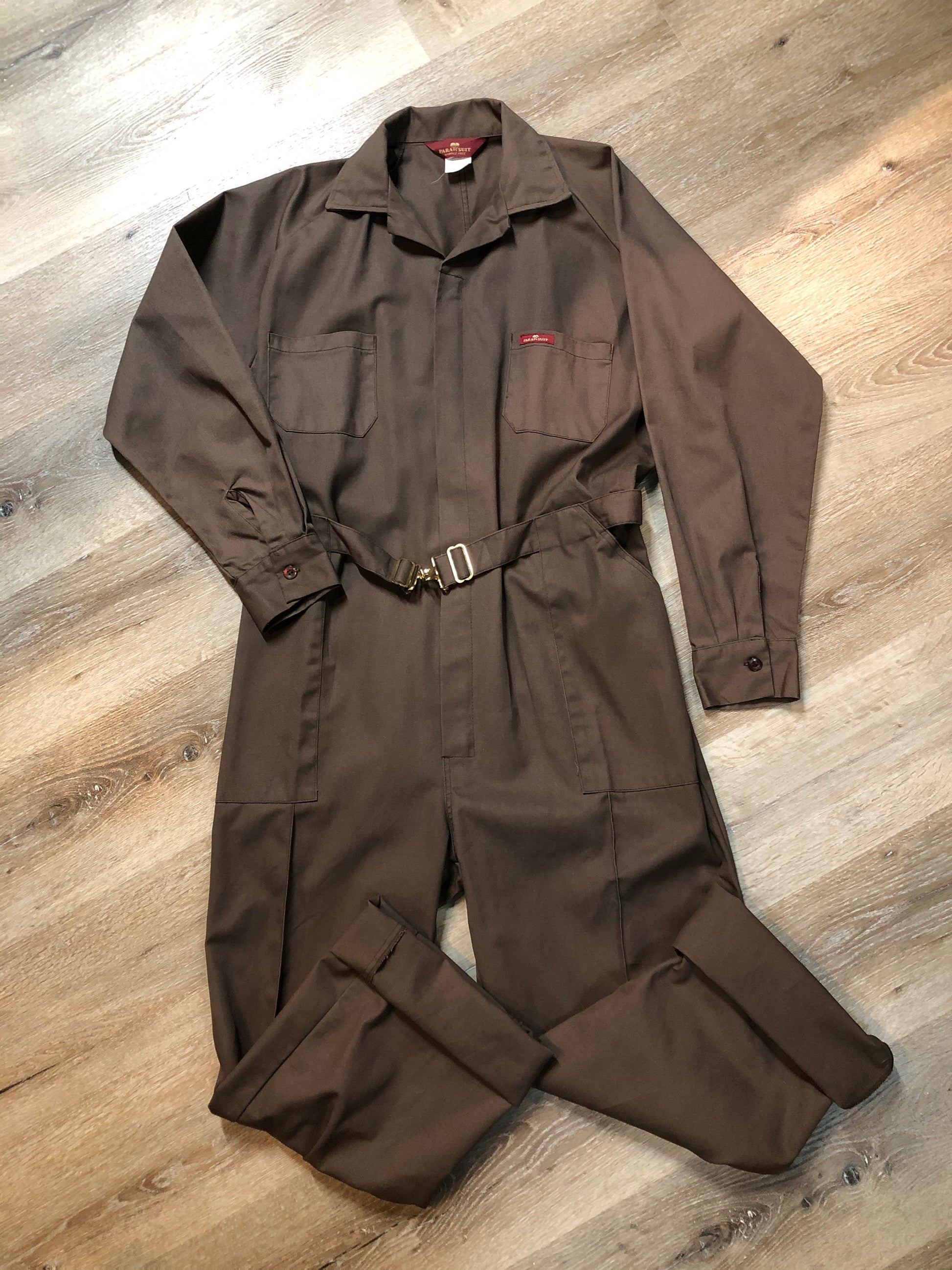 Kingspier Vintage - Parasuit brown wrinkle resistant polyester/ cotton blend coveralls with adjustable belt, snap closures, elastic at the back of the waist, two patch pockets on the chest, front and back. Made in Mexico. Size 46 Regular.