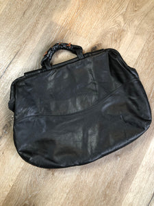 Kingspier Vintage - Upcycled leather bag with top handle, loops to attach a longer strap. (strap not included), snap closures, dinosaur and wooly mammoth design, a tassel and some other unique leather details.

Length - 18”
Width - 4”
Height - 13”

This bag is in great condition with some minor wear.