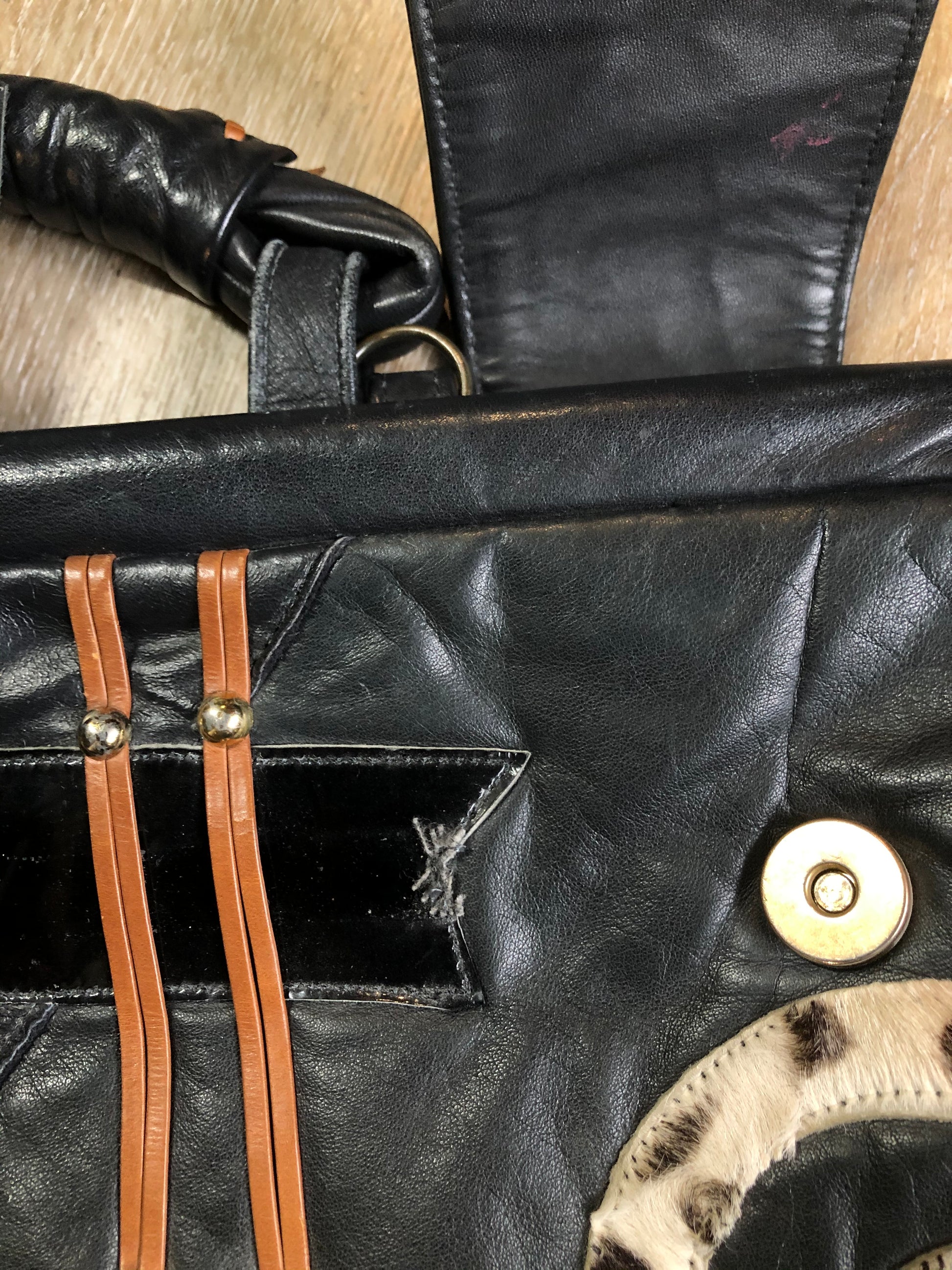 Kingspier Vintage - Upcycled leather bag with top handle, loops to attach a longer strap. (strap not included), snap closures, dinosaur and wooly mammoth design, a tassel and some other unique leather details.

Length - 18”
Width - 4”
Height - 13”

This bag is in great condition with some minor wear.