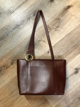 Load image into Gallery viewer, Kingspier Vintage - Georges Sara brown leather handbag with unique brass hardware, zipper top closure with three compartments inside. 

Length - 11.5”
Width - .5”
Height - 9”
Strap - 30”

This purse is in excellent condition.
