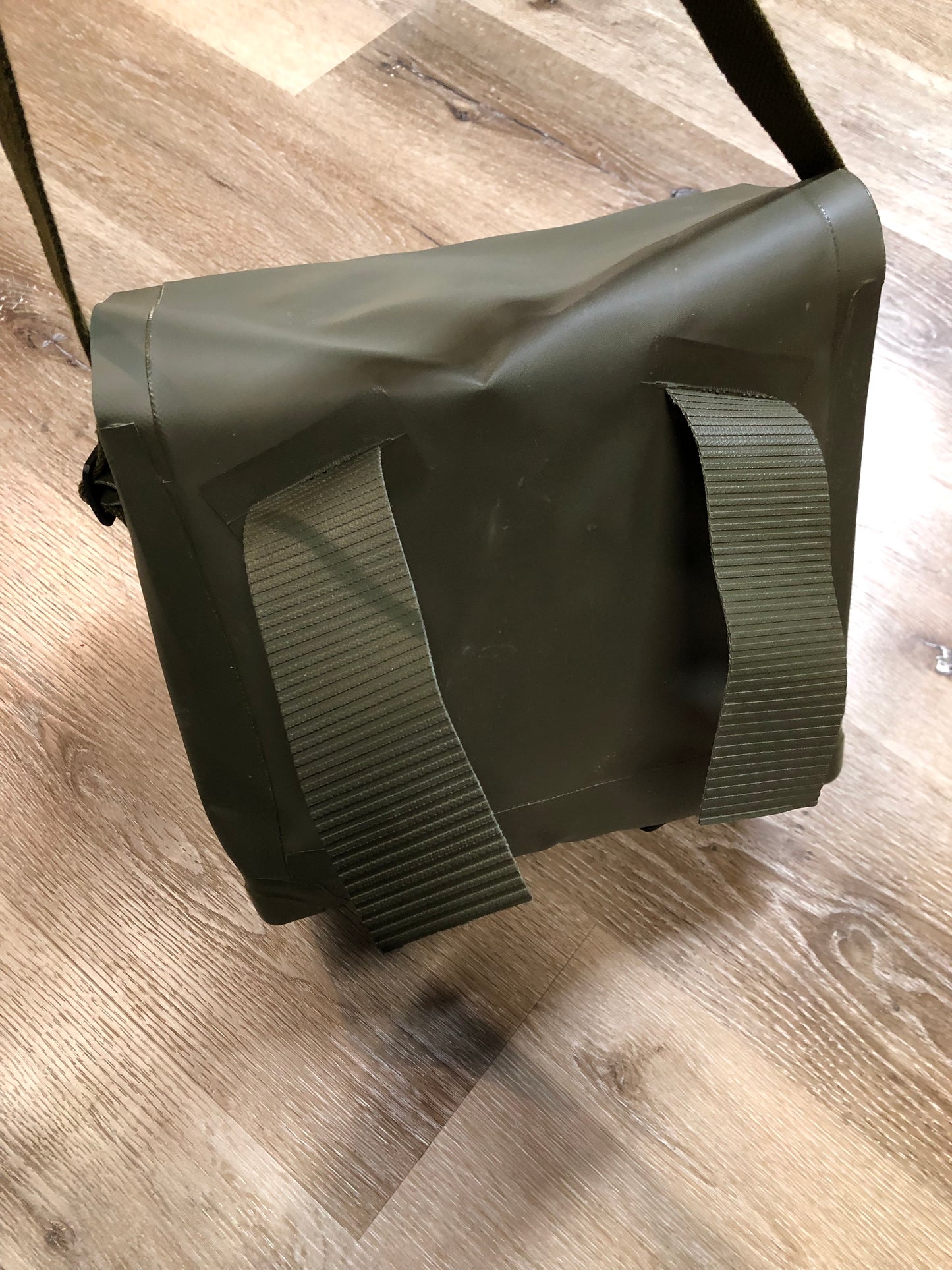 Kingspier Vintage - Deadstock Dutch military issue shoulder bag in dark olive made with waterproof PVC. This bag features a divided main compartment with protective inside flaps that ties in the center and an adjustable canvas shoulder strap.