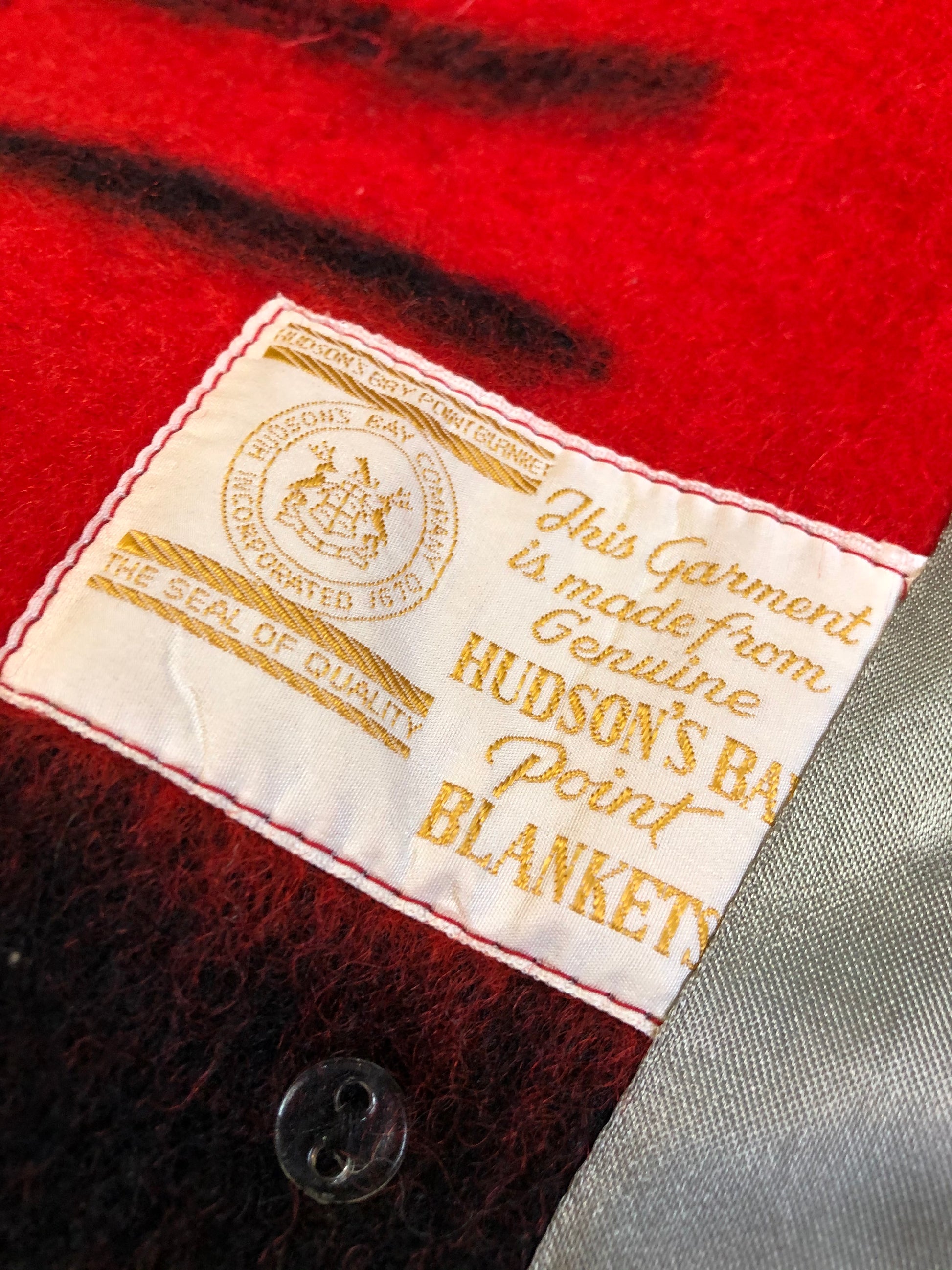 Kingspier Vintage - Genuine Hudson’s Bay Company point blanket coat in red with thick black stripe. The coat features flap pockets and hand warmer pockets, double breasted button closures and belt. Made in Canada. Mens size 48.