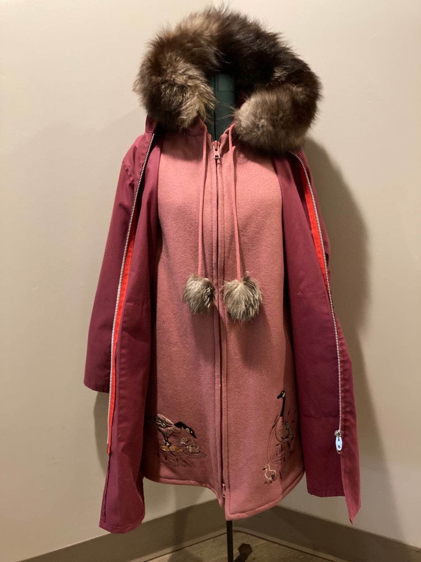 Kingspier Vintage - Vintage Northern Sun light pink 100% wool parka features a removable storm shell, fur trimmed hood, fur pom poms, zipper closures, two front pockets, quilted lining and hand embroidered goose motif on the front, and back of the coat.

Made in Canada.
Size 16/ Large.