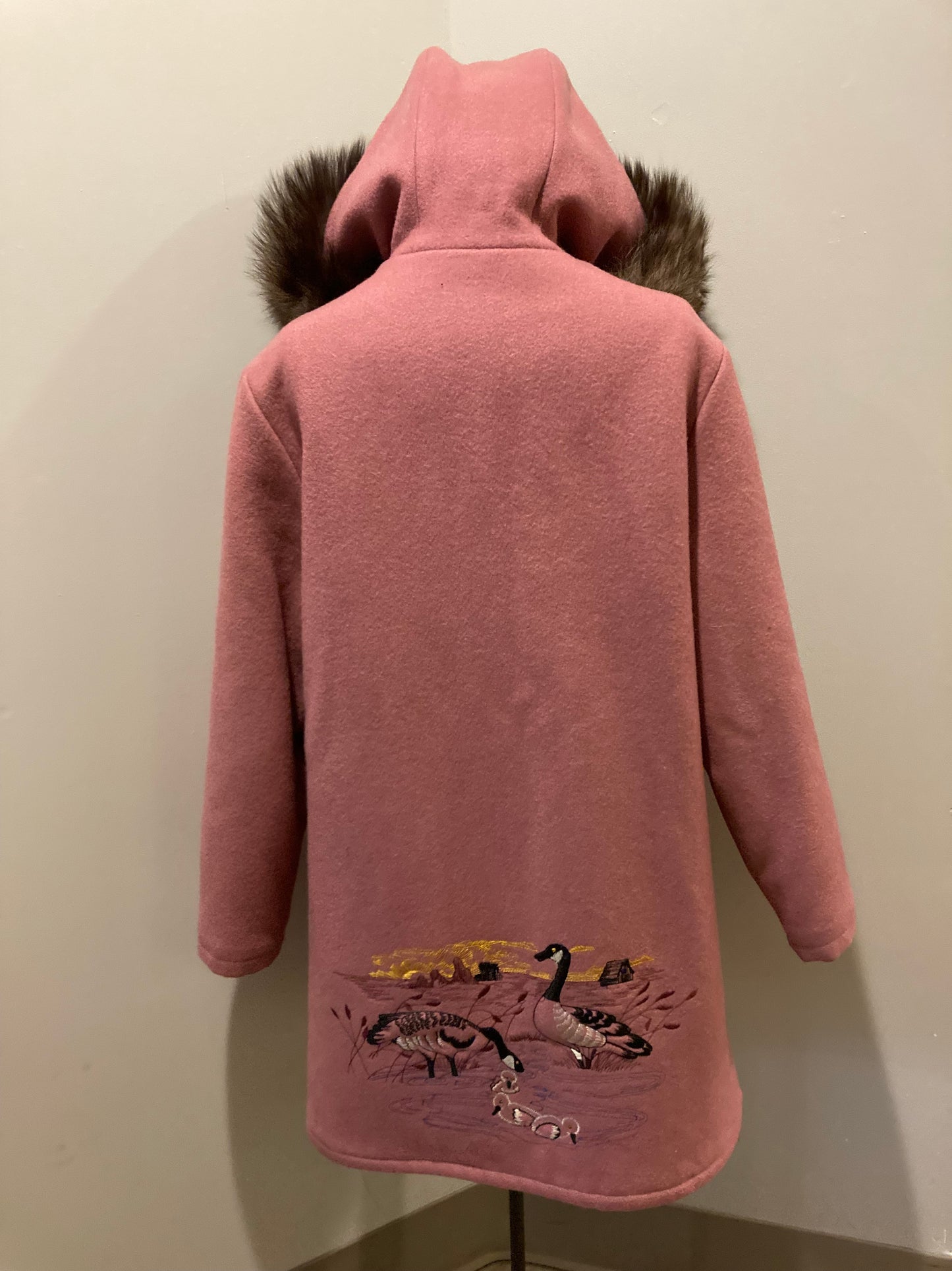 Kingspier Vintage - Vintage Northern Sun light pink 100% wool parka features a removable storm shell, fur trimmed hood, fur pom poms, zipper closures, two front pockets, quilted lining and hand embroidered goose motif on the front, and back of the coat.

Made in Canada.
Size 16/ Large.