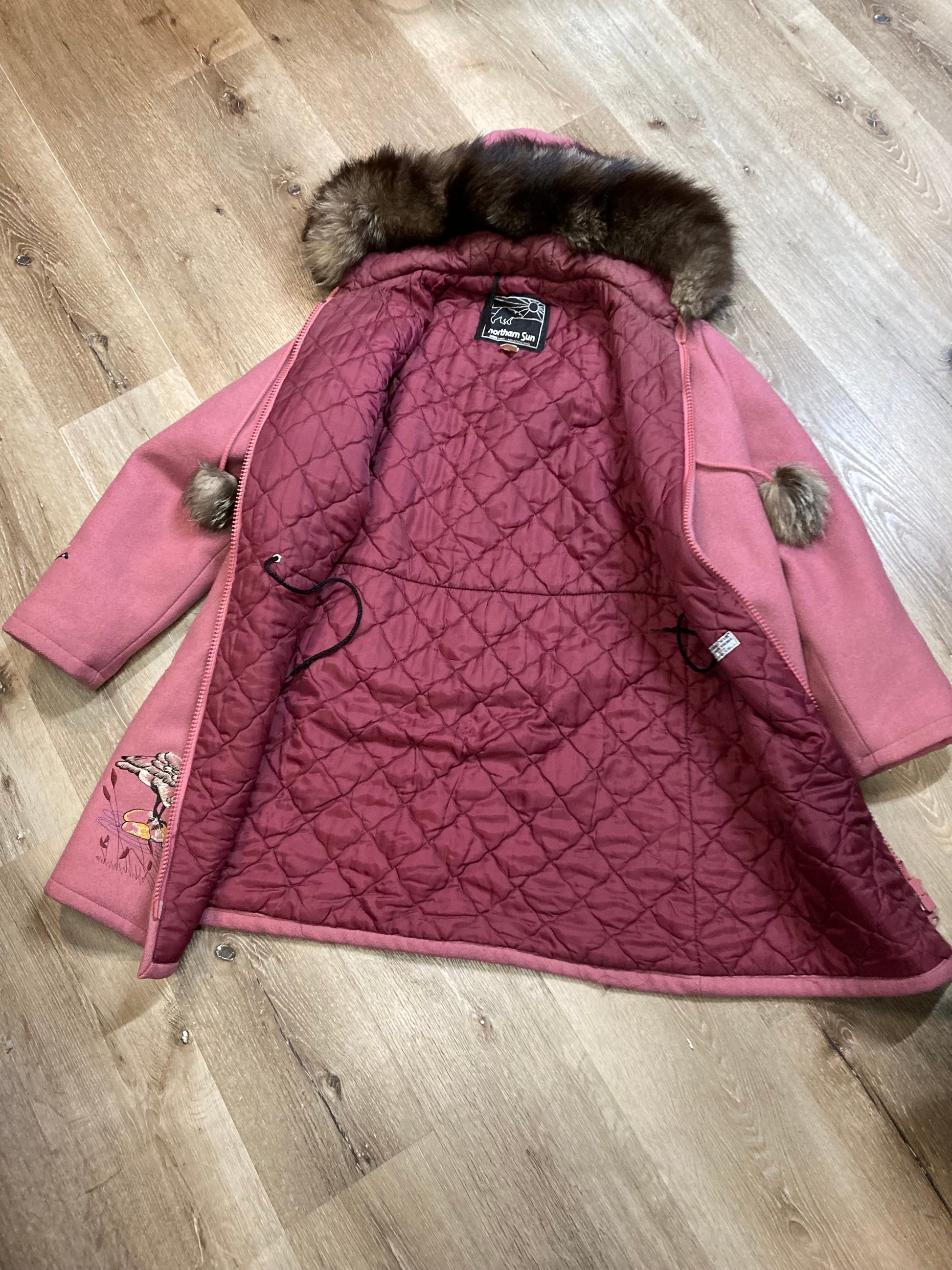 Kingspier Vintage - Vintage Northern Sun light pink 100% wool parka features a removable storm shell, fur trimmed hood, fur pom poms, zipper closures, two front pockets, quilted lining and hand embroidered goose motif on the front, and back of the coat.

Made in Canada.
Size 16/ Large.