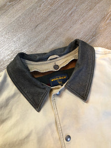 Kingspier Vintage - Woolrich beige chore jacket with cotton shell, leather collar, wool blend lining, snap closures and two flap pockets. Size XL.

