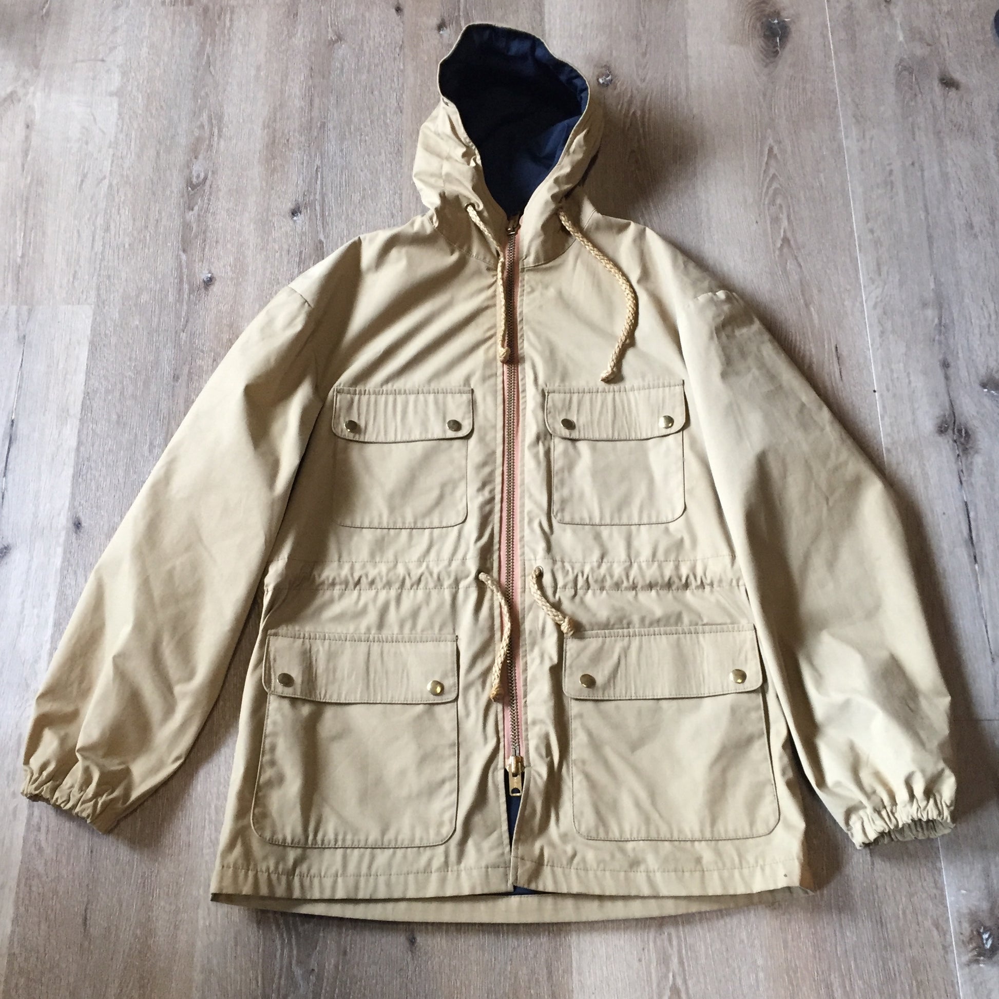 Kingspier Vintage - 1960s Vintage Zero King storm jacket in beige with hood, zipper closure, four flap pockets on the front, drawstring at the waist. Made in USA. Size 44.
