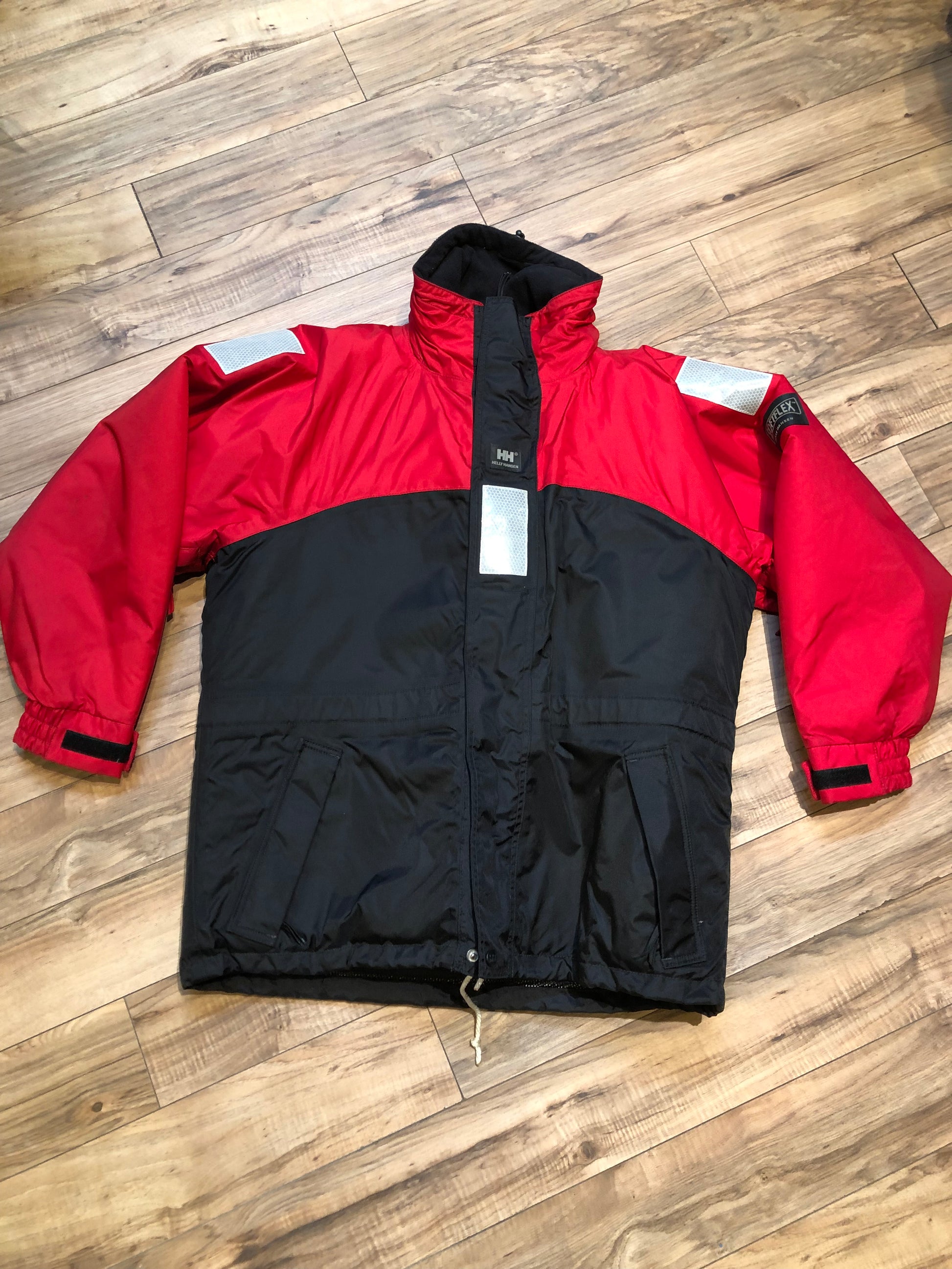 Kingspier Vintage - Helly Hansen red and black Soft Flex Echo Parka with Personal Flotation Device, Canadian Coast Guard approved.

Jacket features a packable hood, adjustable storm collar, zipper and snap closures, zip front pockets, waterproof shell, and PVC foam buoyant component.

Size Small.