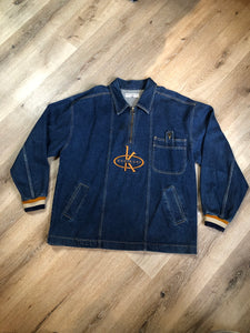 Kingspier Vintage - Vintage Knockout Jeans pullover denim jacket in a medium wash with quarter zip closure, embroidered logo on the front, knit cuffs, slash pockets, one patch pocket on the chest and a leather patch on the back. Size Xl. Made in USA
