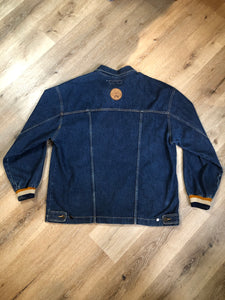 Kingspier Vintage - Vintage Knockout Jeans pullover denim jacket in a medium wash with quarter zip closure, embroidered logo on the front, knit cuffs, slash pockets, one patch pocket on the chest and a leather patch on the back. Size Xl. Made in USA
